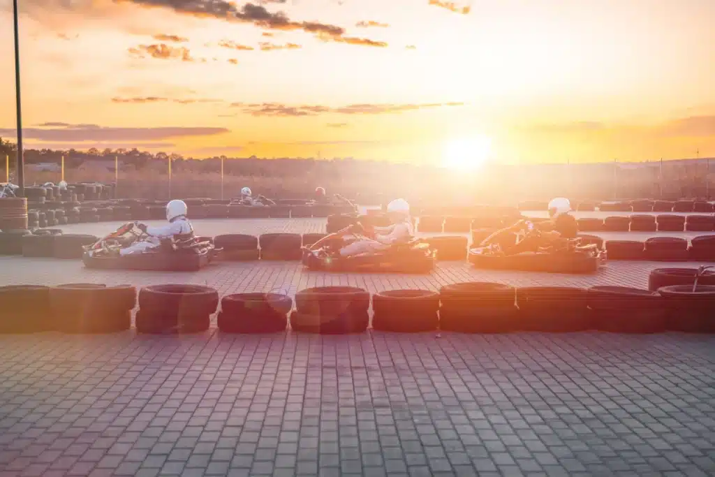 Un groupe de personnes s'amusant à faire du karting au coucher du soleil, créant une ambiance festive et dynamique.